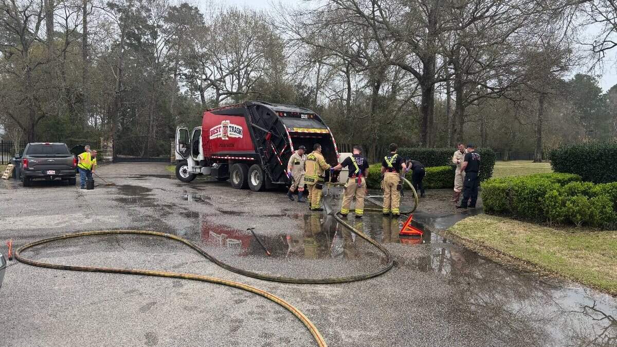 Sanitation workers and firefighters in a Texas neighborhood where a container of acid burst in a trash truck, exposing one worker and requiring a hazmat team to respond.