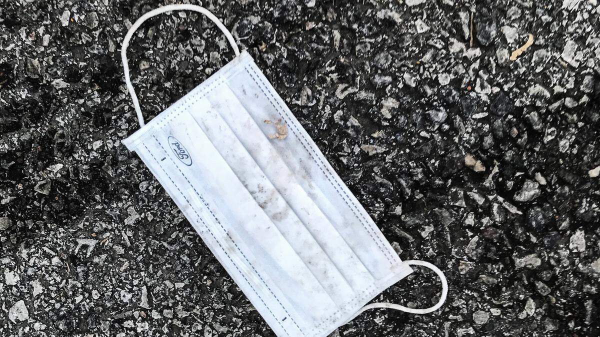 A discarded mask rests on the pavement of a Johnson County grocery story parking lot.
