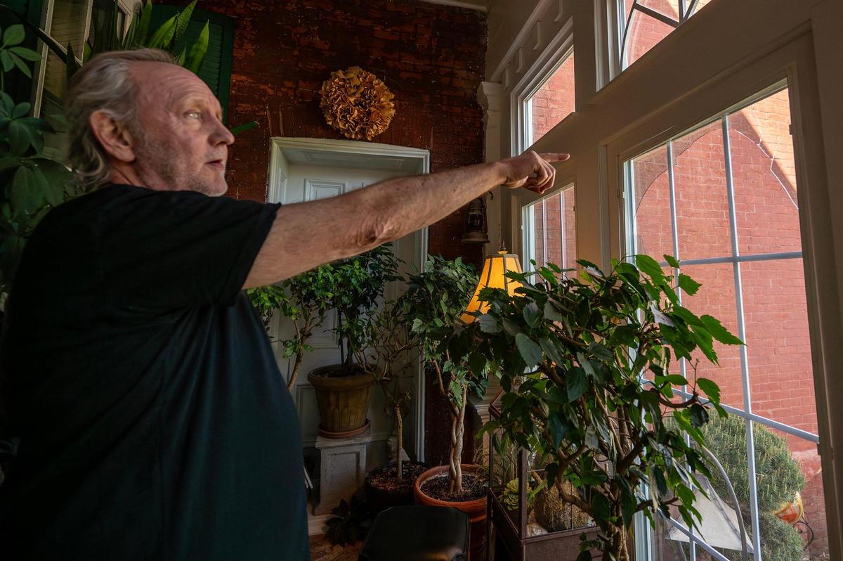 George Stier of Lexington points through a window damaged from a gas line explosion that rocked his house and killed 5-year-old Alistair Lamb in his home on April 9, 2025.