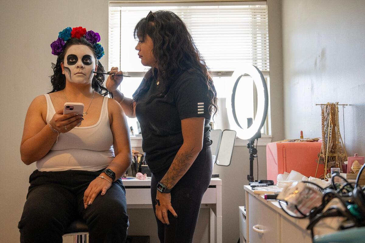Yulissa Lopez sits patiently as she gets her face painted as a Catrina by Daniella Briones.