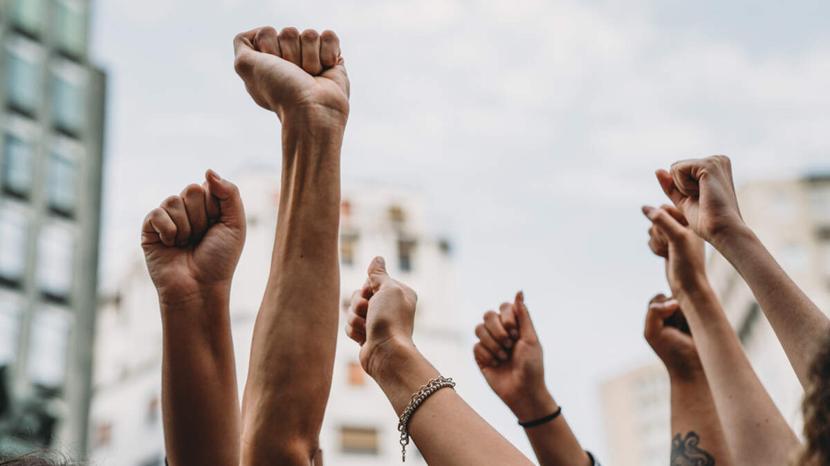 People with raised fists at a demonstration in the city. Multi-ethnic group of people together on strike. protest