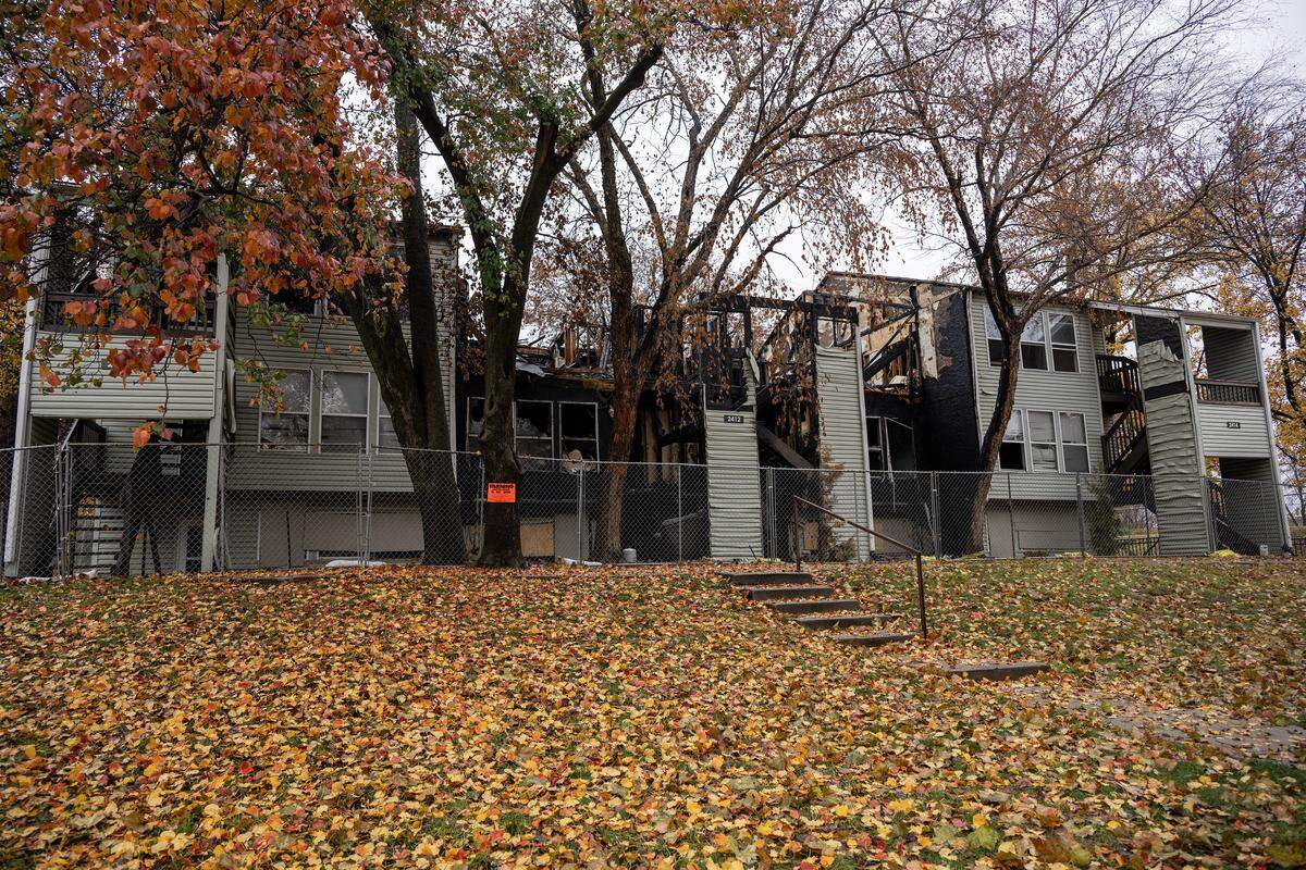 A fire-damaged and condemned building at Olive Park Village Apartments is seen behind a security fence on Friday, Nov. 21, 2025, in Kansas City.