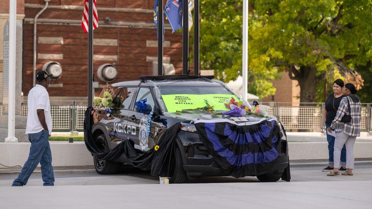 People stop to view the police cruiser driven by slain KCKPD officer Hunter Simoncic set up as a memorial in front of Kansas City, Kansas City Hall on Wednesday, Aug. 27, 2025.
