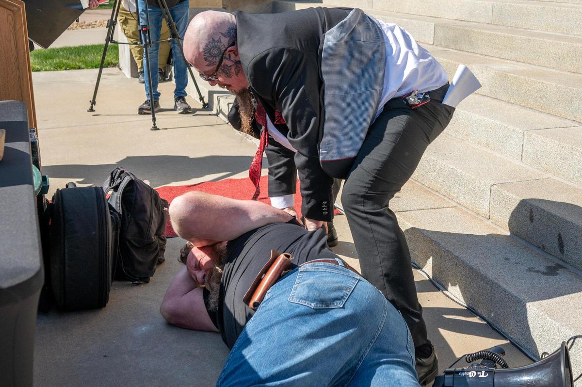 A counter-demonstrator attempts to disrupt a Black Mass ritual as Satanic Grotto leader Michael Stewart, top, conducts the ceremony at the Kansas State Capitol on Friday, March 28, 2025, in Topeka.