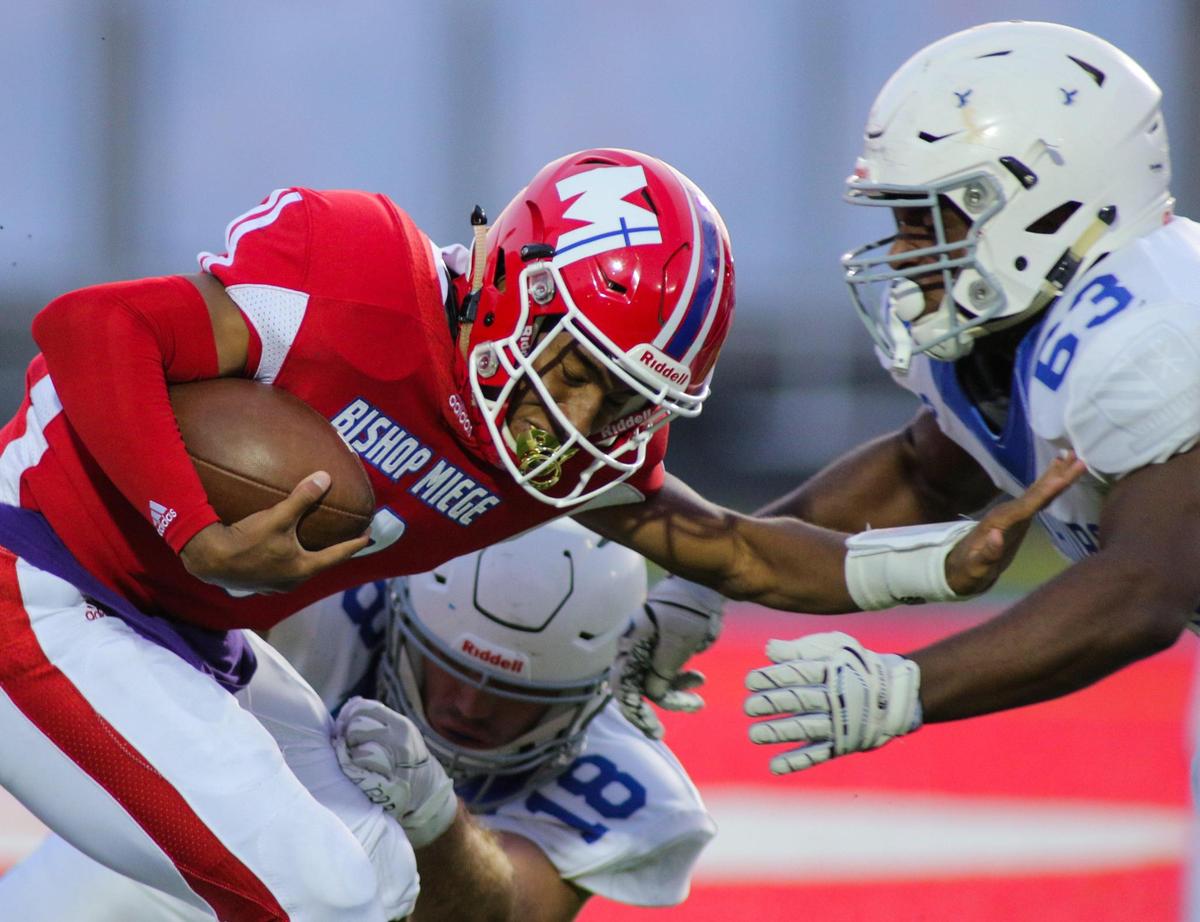 Tyler Tobertson and Johnny Pascuzzi of Rockhurst (in white) take down Bishop Miege quarterback Timothy Dorsey for a sack in the first quarter of Friday night’s game at Dixon Doll Stadium. The Hawklets had a 28-7 lead at halftime.