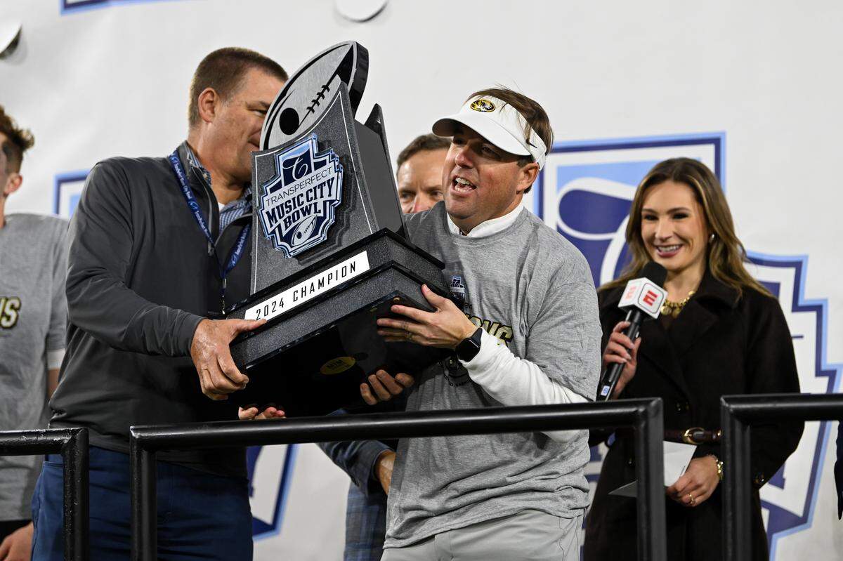 Coach Eliah Drinkwitz of the Missouri Tigers holds the trophy after beating the Iowa Hawkeyes in the TransPerfect Music City Bowl at Nissan Stadium on December 30, 2024 in Nashville.