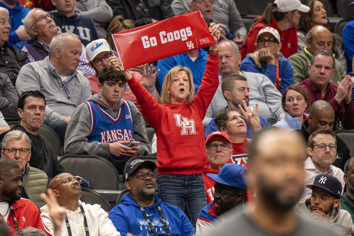 A Houston Cougars fan lifts a banner and cheers during the second half of a Big 12 Men's Basketball Tournament game against the BYU Cougars at T-Mobile Center on Thursday, March 12, 2026, in Kansas City.