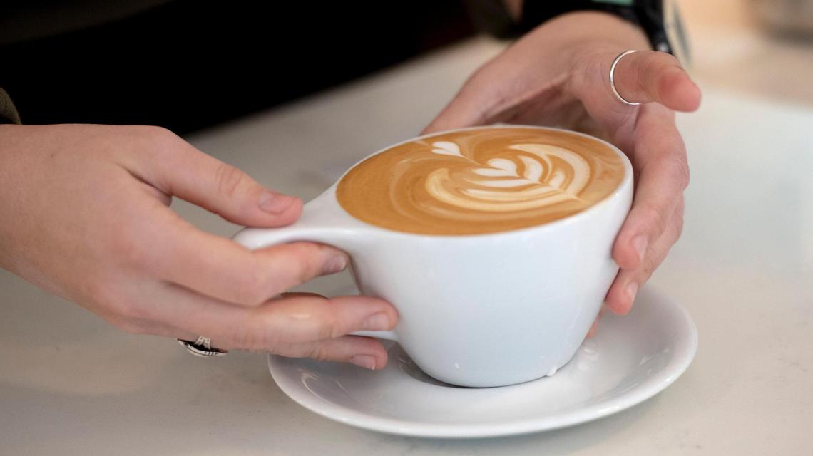 Lydia Gough, assistant manager at Post Coffee Company, sets a latte on the counter for a customer on Tuesday, Nov. 15, 2022, in Kansas City.