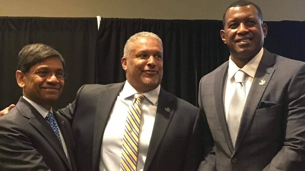 KC Roos men’s basketball coach Marvin Menzies, center, is flanked to the left by UMKC chancellor C. Mauli Agrawal and to the right by UMKC athletic director Dr. Brandon Martin.