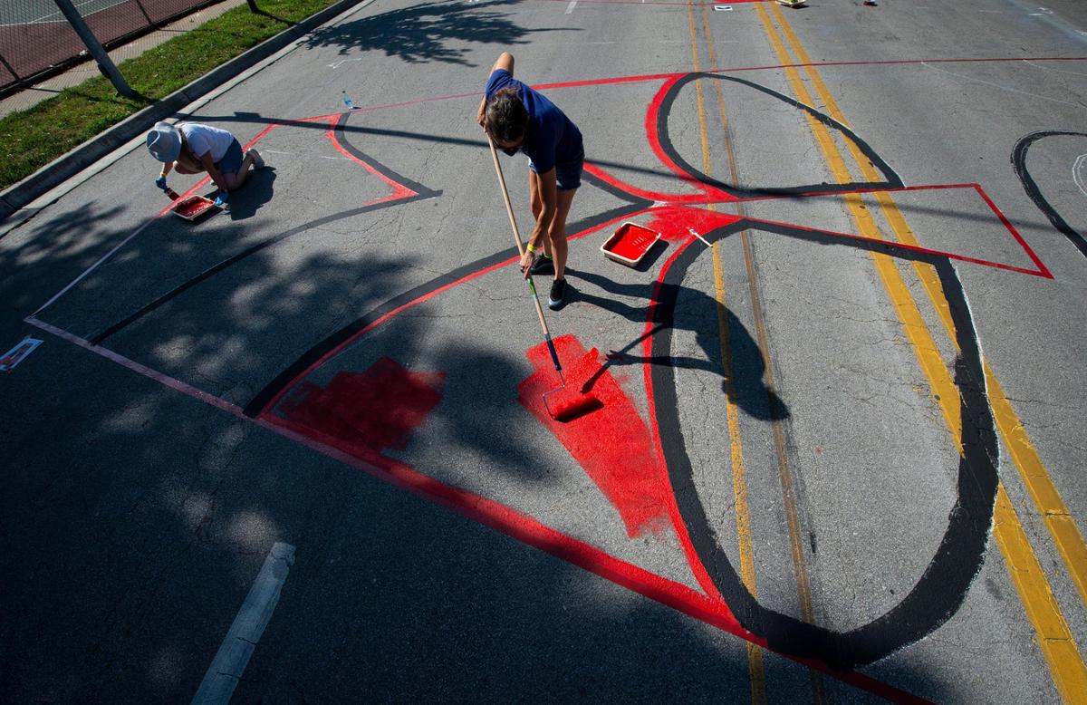 Liz Higgins, Lenexa, rolled out some bright red paint to make a giant “A” that is part of the Black Lives Matter mural painted on Brookside Blvd. Saturday near 63rd St.
