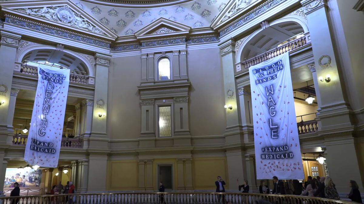 Several protestors unfurled banners in the rotunda of the Kansas capitol Wednesday calling for a vote on medicaid expansion by the senate. The banners had the names of Republican leaders on them and inferred that they had blood on their hands.