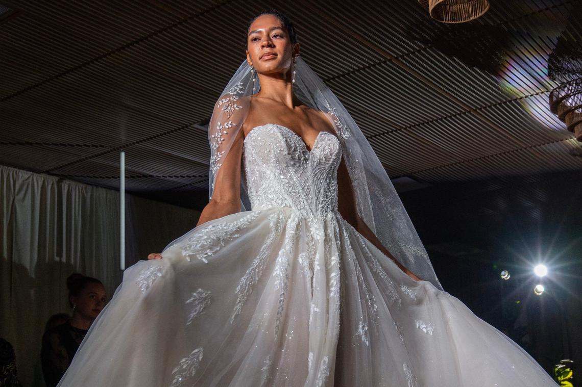 A model walks a runway showcasing a bridal dress during a fashion show as part of the Essense of Australia bridal summit.