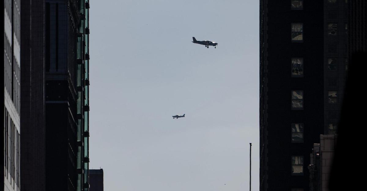 Framed between skyscrapers in downtown Kansas City, two small airplanes prepare to land at the nearby Charles B. Wheeler Downtown Airport.