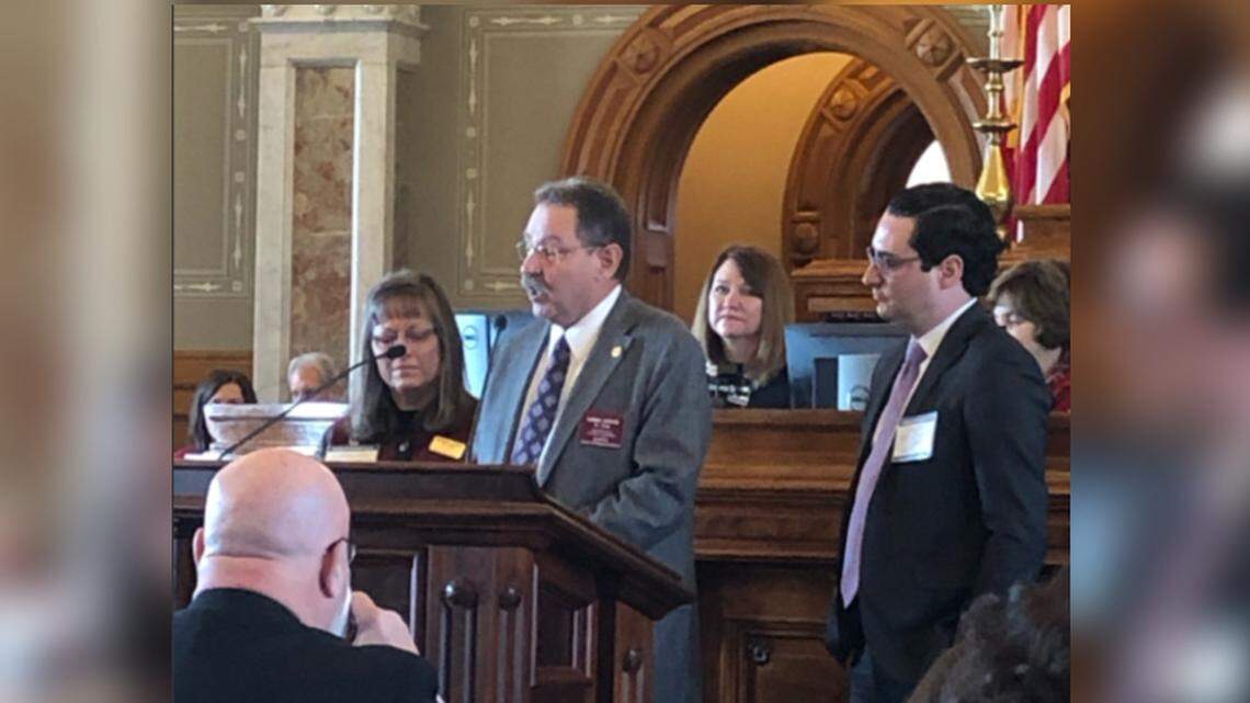 Kansas State Rep. Greg Lewis, a Republican from St. John who is battling cancer, announces his resignation before the Kansas House of Representatives Monday. His wife, Susan, and son, Joshua, stand with him.