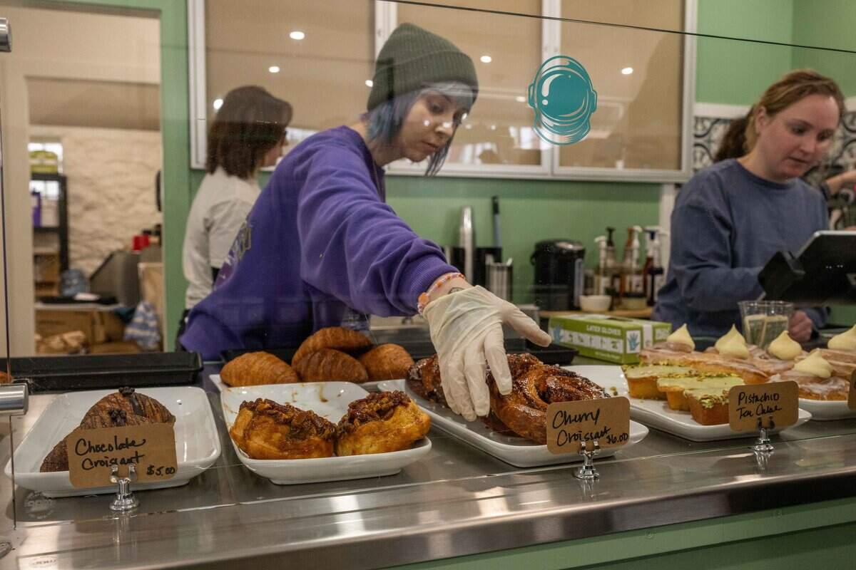 Barista Nicole Summers grabs a pastry for a customer at the soft opening for Bodega Bakery, a new cafe/bodega from the owner's of Blackhole Bakery, on Friday, December 12, 2025, in Kansas City.