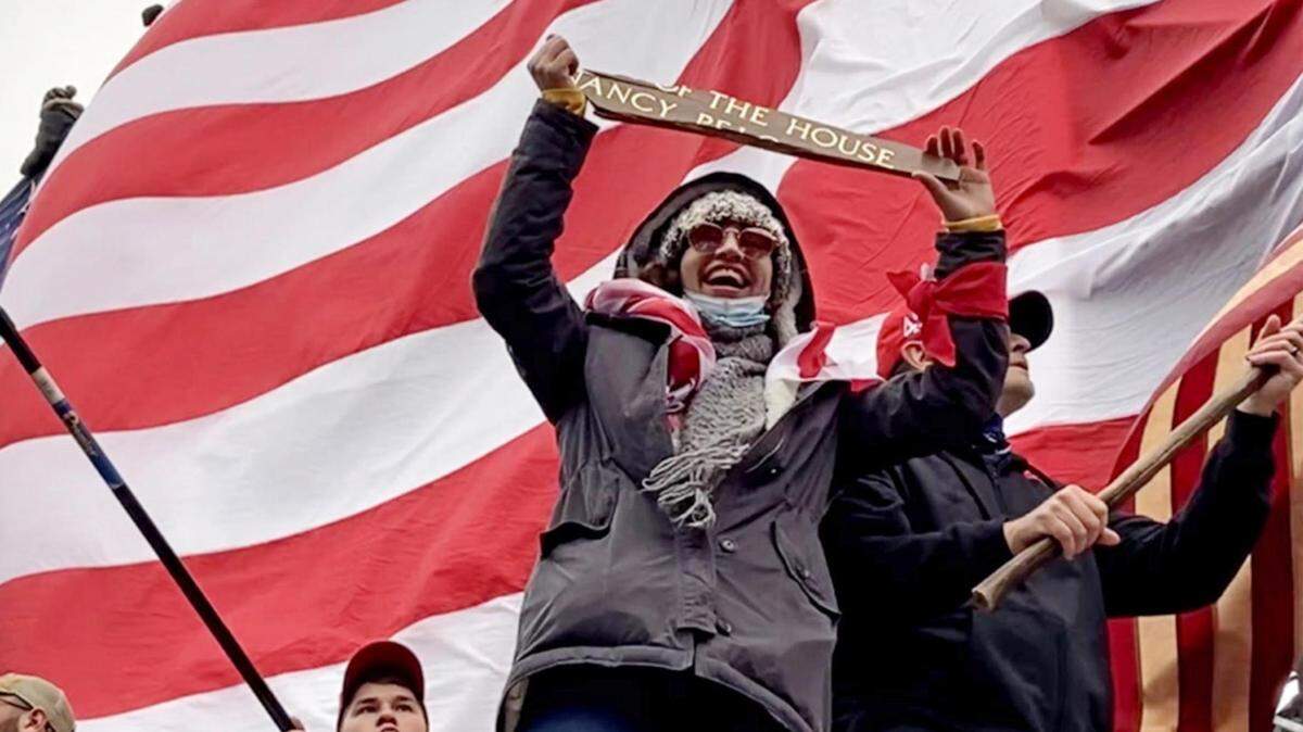 Shortly after exiting the Capitol on Jan. 6, 2021, Emily Hernandez of Sullivan, Missouri, displayed a piece of House Speaker Nancy Pelosi’s office sign for the crowd to see.