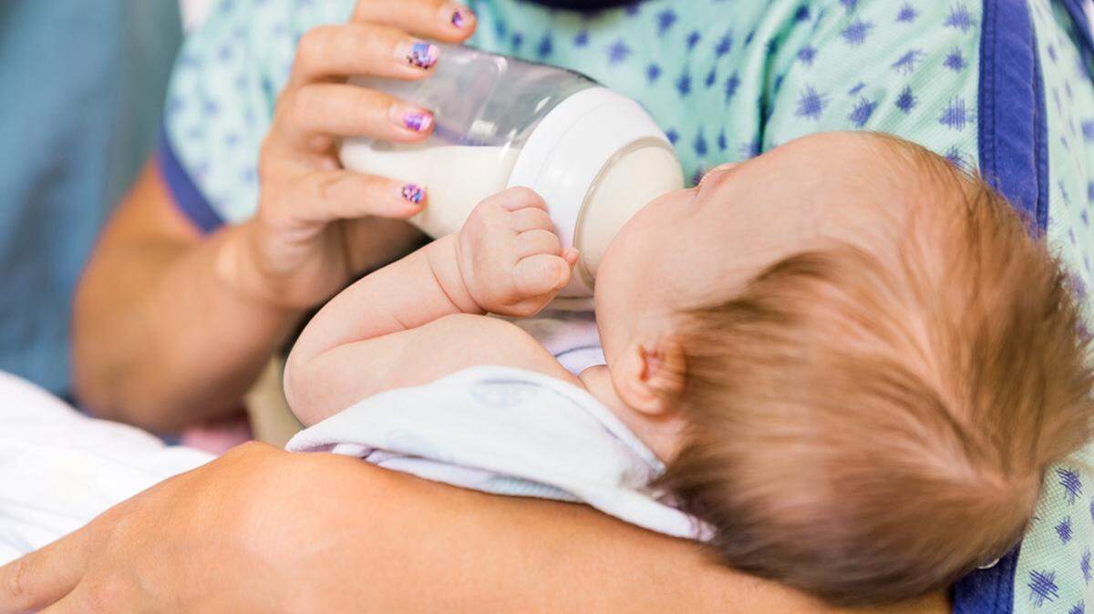 Closeup of caring mother feeding milk from bottle to newborn baby girl in hospital mom baby health care healthcare medicaid missouri postpartum