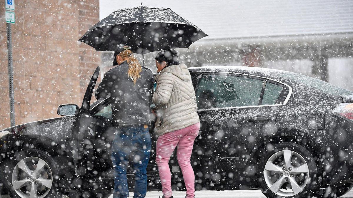 Nancy Varguez of Shawnee held an umbrella as Scott Rinker, an employee of Advance Auto Parts, helped her with a check engine light as snow fell on Monday, Jan. 8, 2024, in Shawnee, Kansas.