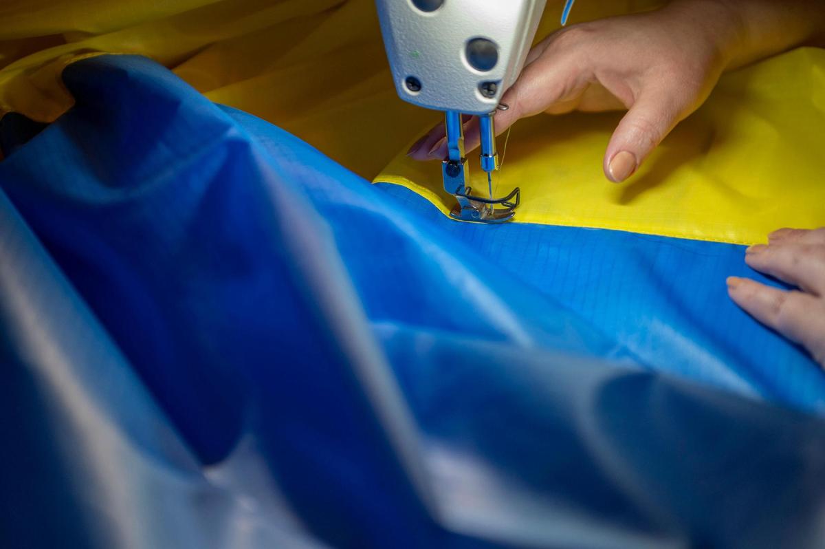 Olga Potapenko sews yellow and blue fabric to help make Ukrainian flags at her home in Independence on Thursday, March 3, 2022. Potapenko is a wedding dress designer who has opened her home to help create Ukrainian flags as a thank you to anyone who has donated to support Ukraine.