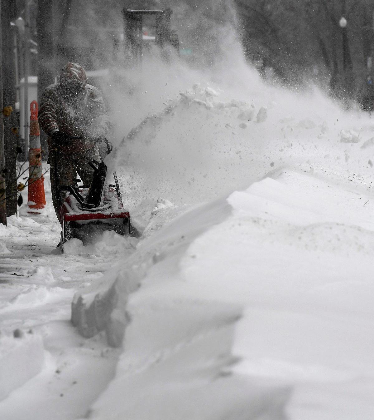 Windblown snow engulfs Izzy Licos while he uses a snow blower to clear a drift from the sidewalk of a business Sunday, Jan. 5, 2025, in downtown Overland Park. Blizzard conditions hit the Kansas City metro crippling transportation and shutting down several businesses.