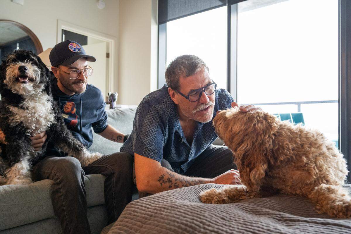 Kris Saim and his husband, Anthony, play with their dogs in their home on Friday, April 10, in Kansas City. Saim has Stage 4 terminal cancer and is recording a podcast, Dying Out Loud, that talks about death. Saim's husband helped spur the idea of recording about the subject, and is also a producer on the podcast.