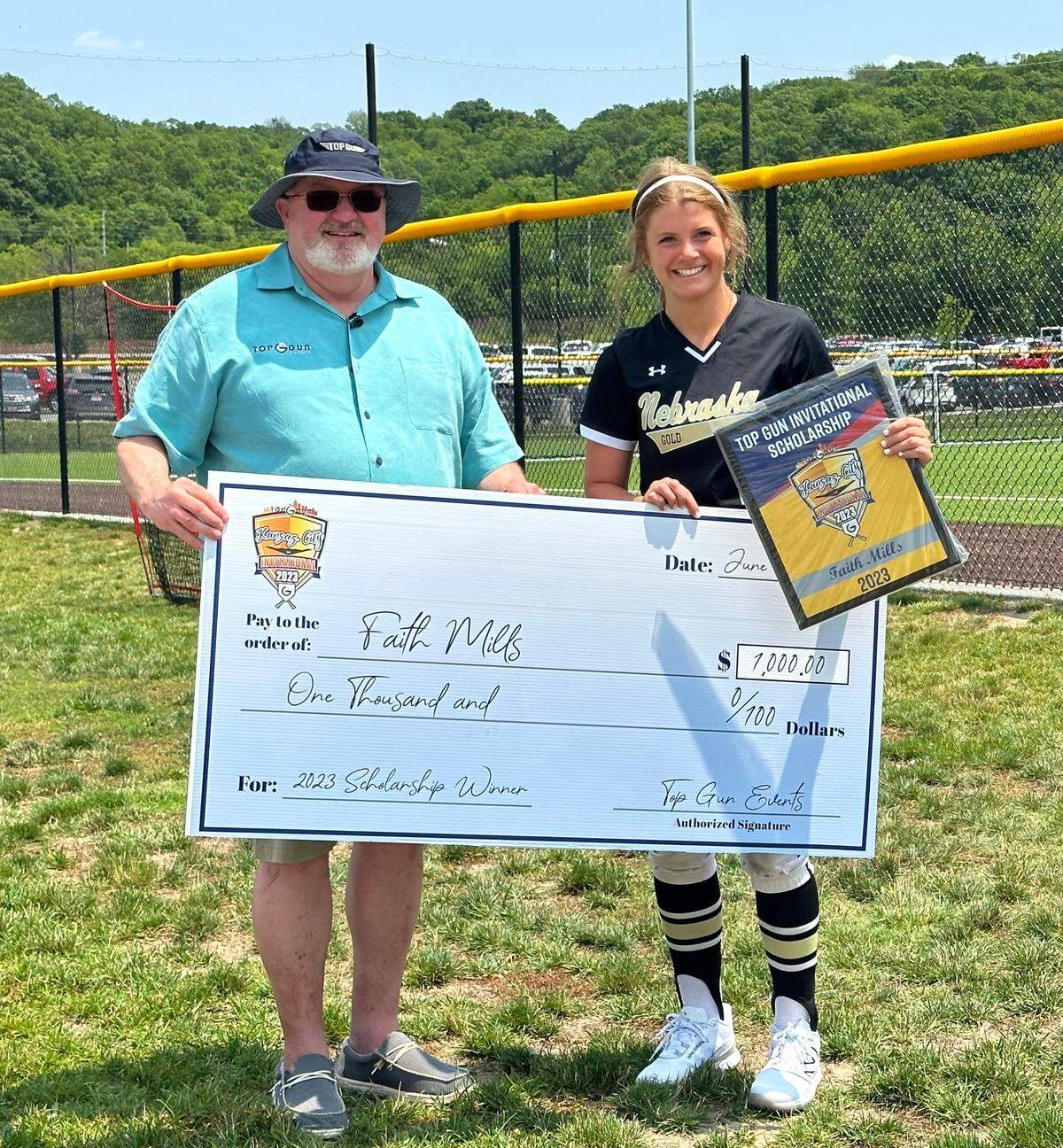 Top Gun Invitational founder Robb Behymer and scholarship winner Faith Mills of Nebraska Gold 18u hold up her award at the softball tournament in the KC-area on June 15, 2023.