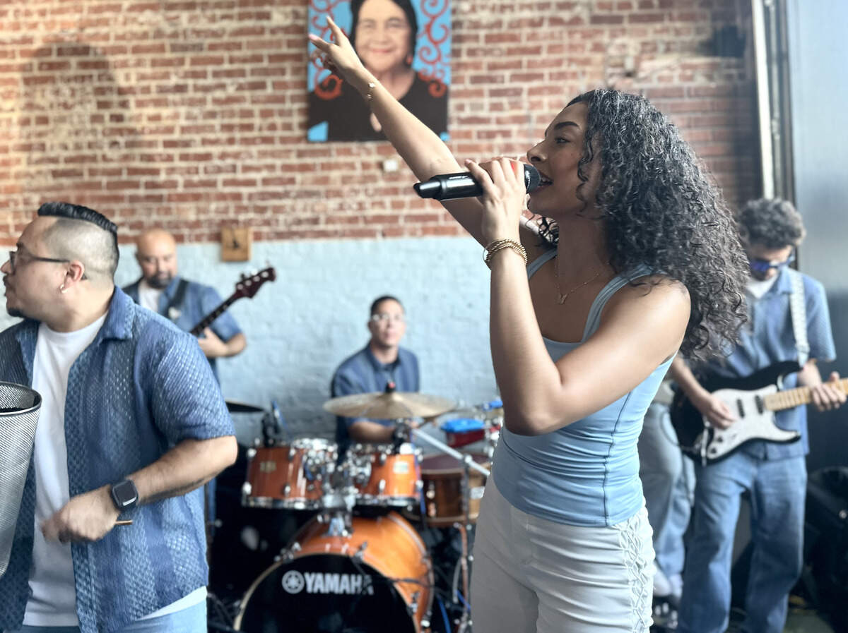 Valeria Navarrete, a singer for Selekto Show, reaches her hand in the air as she sings. Selekto Show have been together for two years, and they specialize in cumbia, bachata, salsa and merengue.