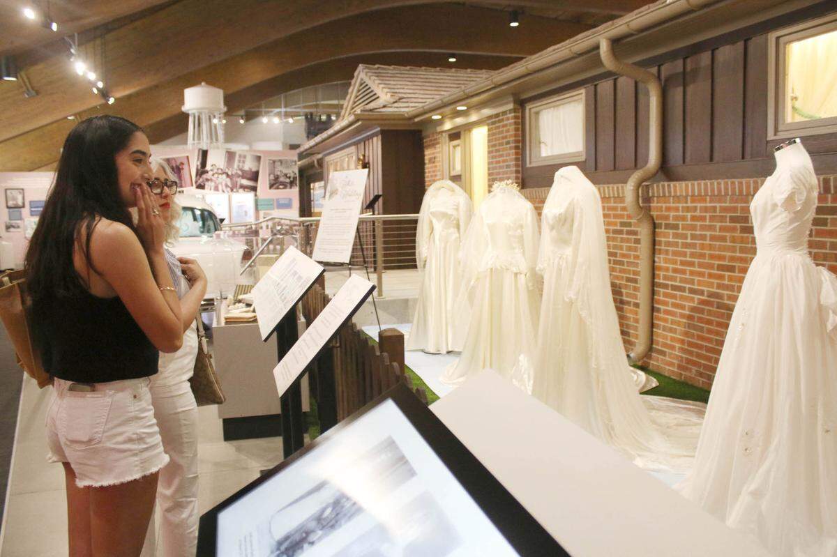 Overland Park residents Romina Martinez and Karina Canales look at some of the wedding dresses outside the All-Electric House at the Johnson County Museum that are on display as part of a new exhibit on how weddings changed just after World War II.