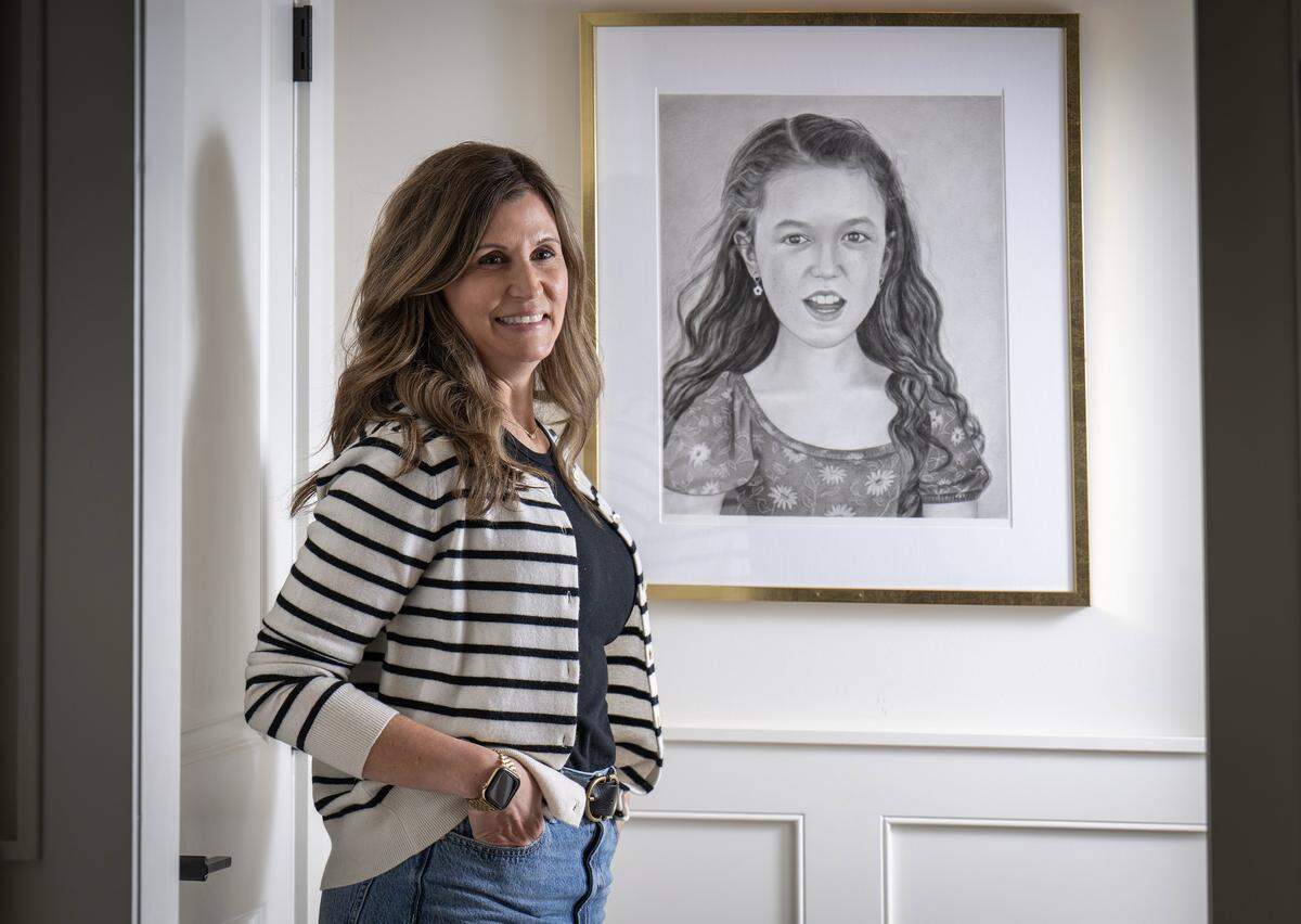 Sara Bloomfield stands with a portrait of her daughter, Olivia, at her home in Leawood, Kansas, on Wednesday, April 1, 2026. Olivia, who was born with and lived with Congenital Muscular Dystrophy, was a champion for accessibility and inclusion in playgrounds and bathrooms across Kansas City. Through her foundation, the Olivia Bloomfield Foundation, Sara continues the work they started together, honoring Olivia's legacy.