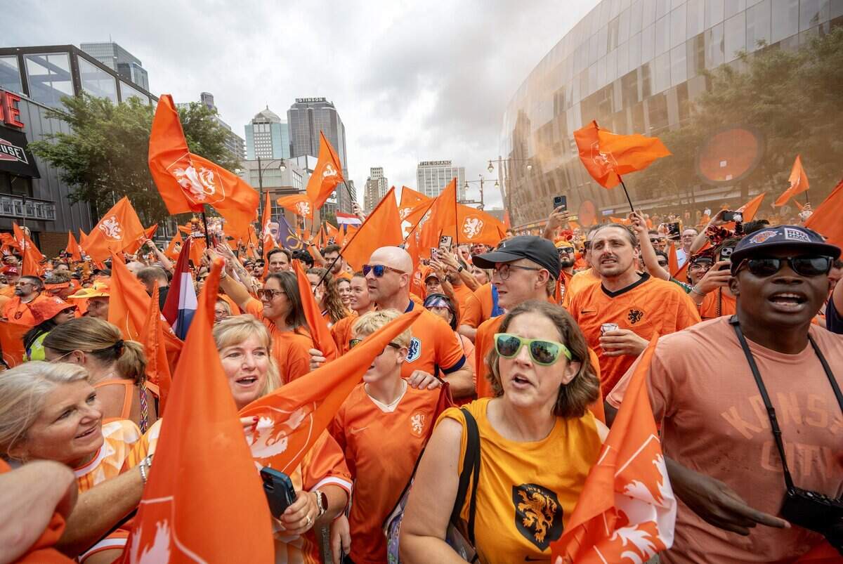 Orange smoke bombs erupt as fans celebrate and wave Netherlands flags during the Orange Walk on Thursday, June 25, 2026, in Kansas City.