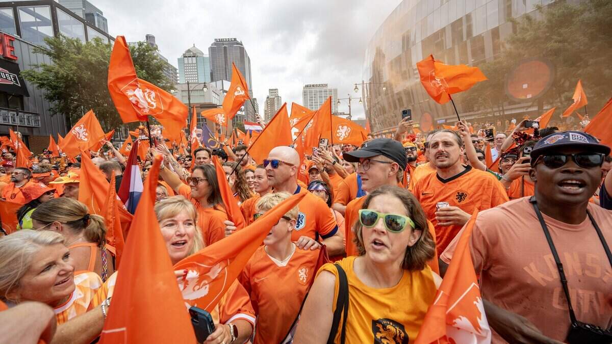 Orange smoke bombs erupt as fans celebrate and wave Netherlands flags during the Orange Walk on Thursday, June 25, 2026, in Kansas City.