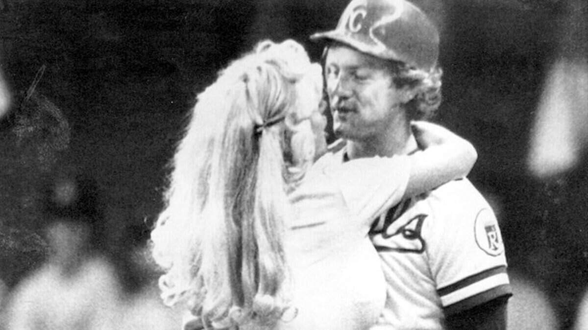Caption: Special Section. Hall of Fame Edition. Kansas City Royals. George Brett The Legacy. Baseball. CUTLINE Morganna the kissing bandit wasn’t the only one to embrace George Brett. He has had a special place in Kansas City’s heart. Photographer: ASSOCIATED PRESS Date: 19990725 Category: S CUTLINE Upper Deck has recalled trading cards that likened Hillary Clinton to Morganna the Kissing Bandit, who had a fondness for George Brett. Star Magazine Caption Contest. This year’s theme: Kansas City Royals Baseball. Winners soon in Star Magaine. CUTLINE A. Results of the StarMag Royals-themed Caption Contest. Winners. A. The winner. “I work for the Royals, not the twins.” Lila Curnutte, Amsterdam. Mo. We promised to tell you what the actual photo captions were, but for this one we’re not sure of the year (possibly 1977). But obviously this is Royals great George Brett being manhandled by Morganna the Kissing Bandit, who was famous for two things. Well, three: She liked to gallop out on ball diamonds to smooch the athletes. (She reportedly got to Brett twice.) Her career started in 1971, but Morganna has been MIA from pro sports fields since the late ’90s. ASSOCIATED PRESS