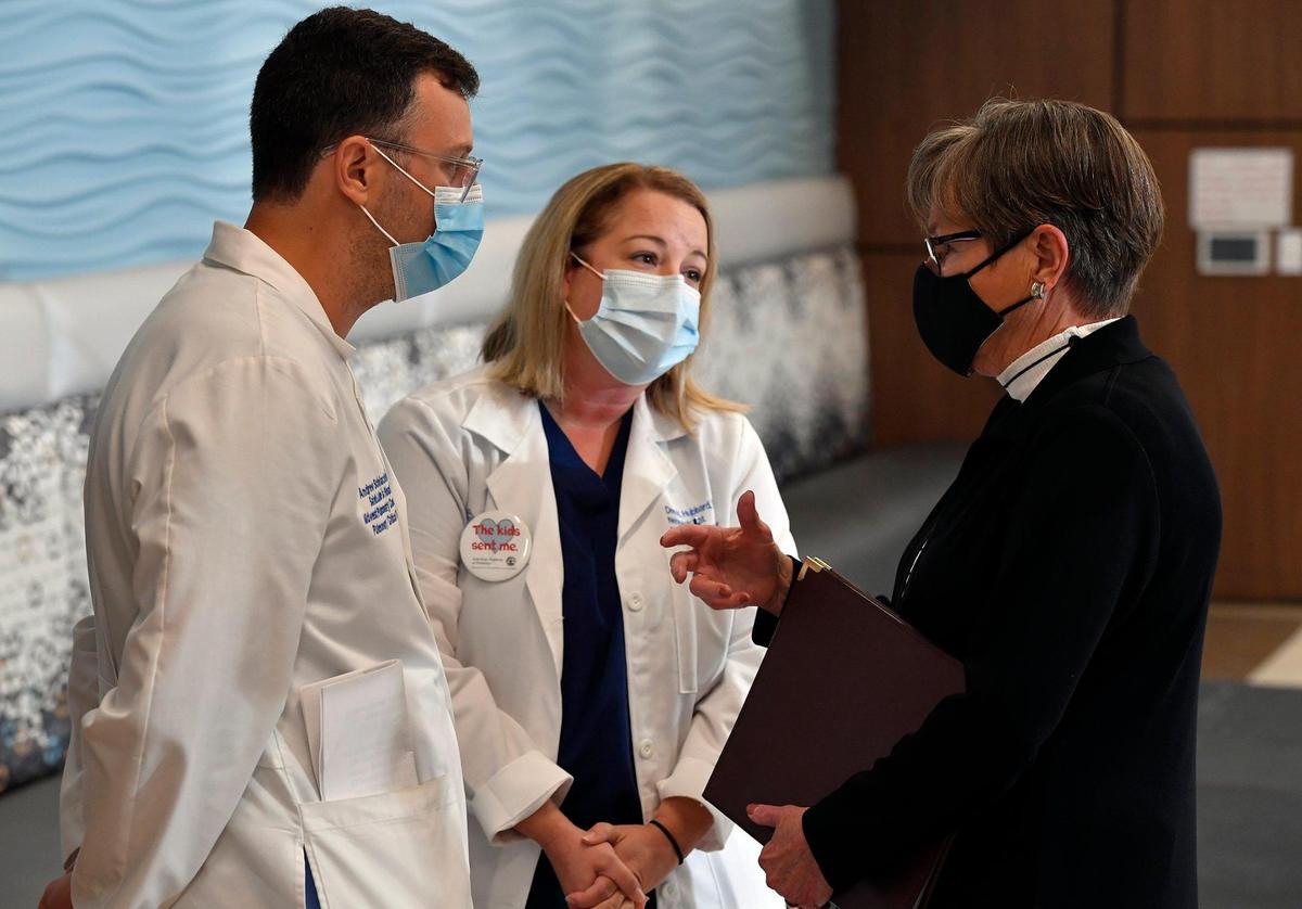 With hospitals across the state and country overflowing with COVID-19 patients, Kansas Governor Laura Kelly, right, on Friday urged Kansans to get a COVID vaccination to help prevent further spread of the virus. Kelly’s comments came during a press conference at St. Luke’s South Hospital in Overland Park. Afterwards, she visited with Dr. Andrew Schlachter, left, and Dr. Dena Hubbard, who also spoke out against disinformation and the need for everyone to get a vaccination.