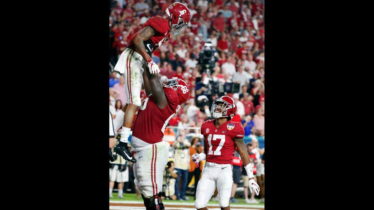 Alabama lineman Lester Cotton Sr. lifts Alabama wide receiver DeVonta Smith into the air after Smith scored a touchdown against Oklahoma Saturday night in Miami Gardens, Fla.