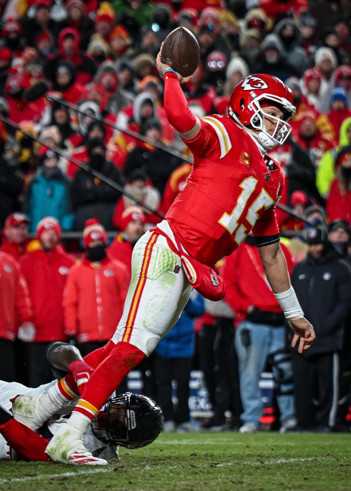 Kansas City Chiefs’ Patrick Mahomes (15) goes down in the grasp of Houston Texans defensive tackle Mario Edwards Jr. while he throws a touchdown pass to tight end Travis Kelce in the fourth quarter during the AFC Divisional Round playoff game on Saturday, Jan. 18, 2025, at GEHA Field at Arrowhead Stadium.