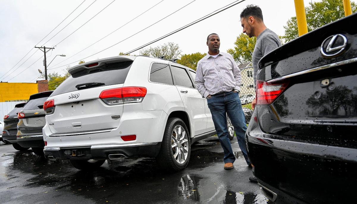 Marcus Watson, left, shows customer Javier Martinez some vehicles for sale at his car dealership, Watson’s Auto Wholesale. Watson sells a variety of used cars but specializes in luxury models, and says his business has grown.
