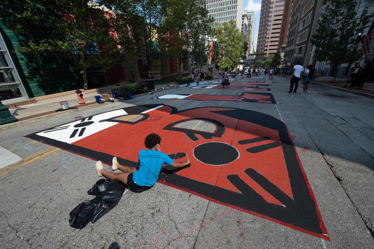 Akina Love, 12, touched up the “B” in the Black Lives Matter mural being painted on 10th St. between Wyandotte and Baltimore Saturday.