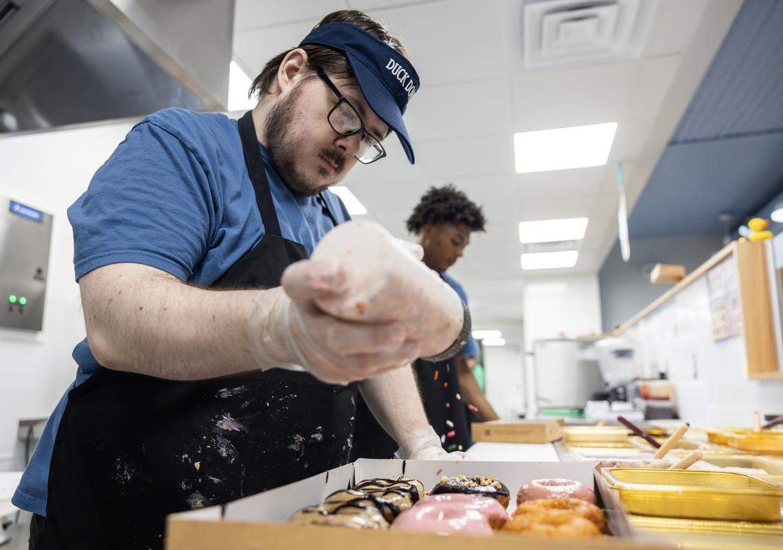 Nolan Miller, an employee at the Lee’s Summit Duck Donuts shop, prepares a box of donuts on Thursday, April 23.