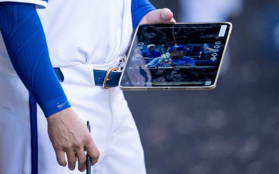 A Kansas City Royals bench coach carries a video review tablet in the dugout during the Royals’ home opener Thursday against the Minnesota Twins.