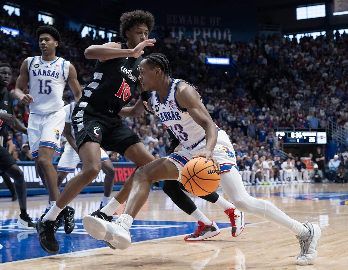 Kansas Jayhawks guard Elmarko Jackson (13) drives past Cincinnati Bearcats forward Baba Miller (18) in the first half Allen Fieldhouse on Saturday, Feb. 21, 2026, in Lawrence, Kansas.