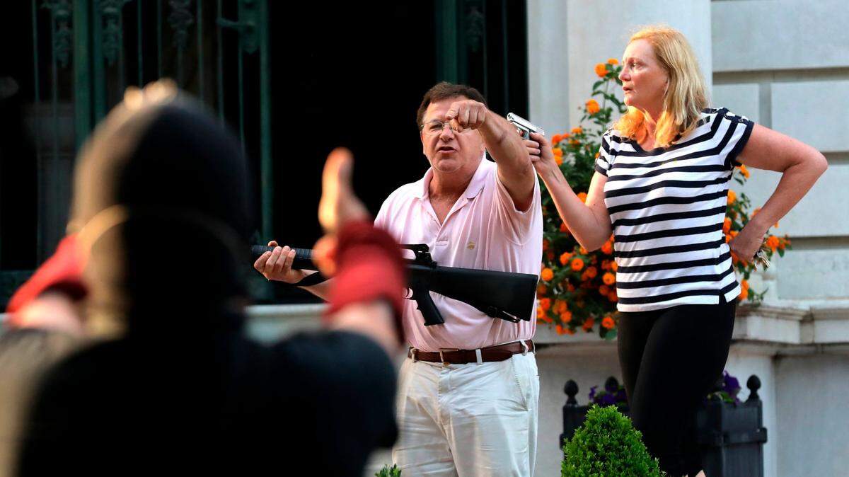 In this June 2020 file photo, armed homeowners Mark and Patricia McCloskey, stand in front of their home to confront protesters marching to St. Louis Mayor Lyda Krewson’s house in the Central West End of St. Louis. They were charged with felony weapons violations, and later pardoned by Gov. Mike Parson. Mark McCloskey, now a Republican candidate for U.S. Senate, testified Tuesday in favor of a bill that would expand the state’s “stand your ground” law. (Laurie Skrivan/St. Louis Post-Dispatc h via AP)