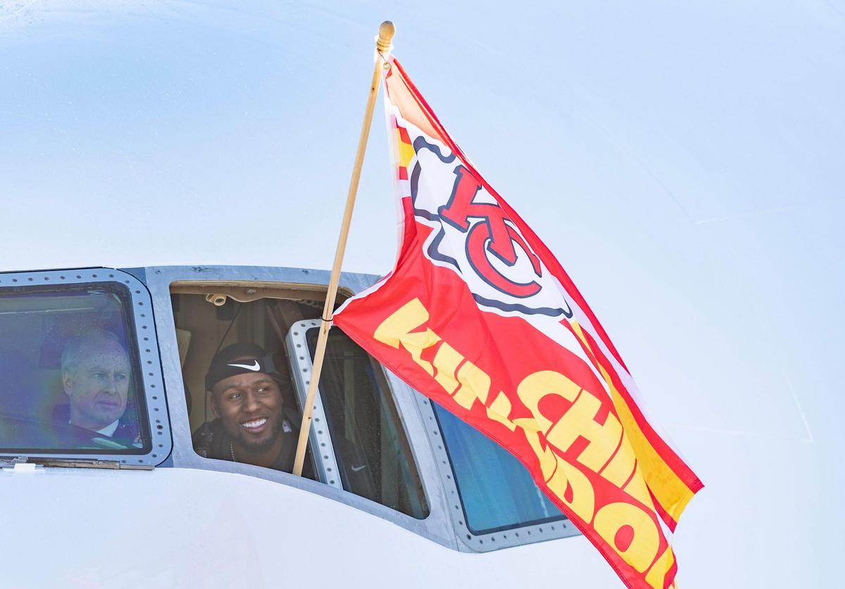 Chiefs defensive end Carlos Dunlap waves a Chiefs Kingdom flag out the window of the team’s charter plane after it arrived at Kansas City International Airport on Monday. The Kansas City Chiefs returned home after defeating the Philadelphia Eagles in Super Bowl LVII in Glendale, Ariz.