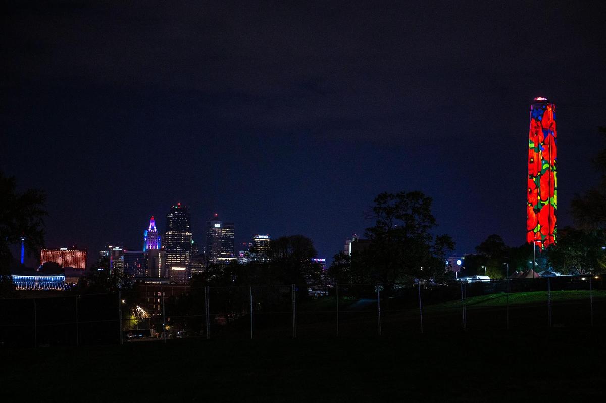 The downtown Kansas City skyline shines north of the Liberty Memorial Tower aglow with images of poppies.