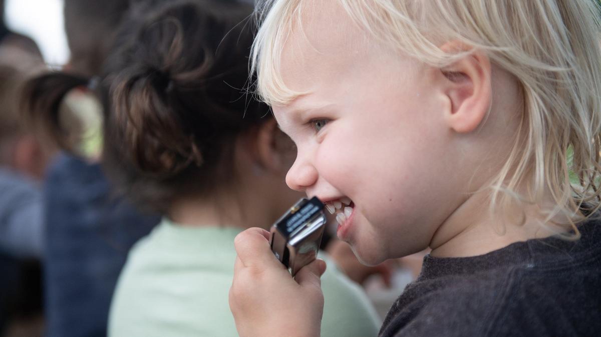 Sidney Yonkey laughs while playing the harmonica at a beginners workshop during Make Music Day on Friday, June 21, 2024, at the Lakeside Nature Center in Swope Park in Kansas City.