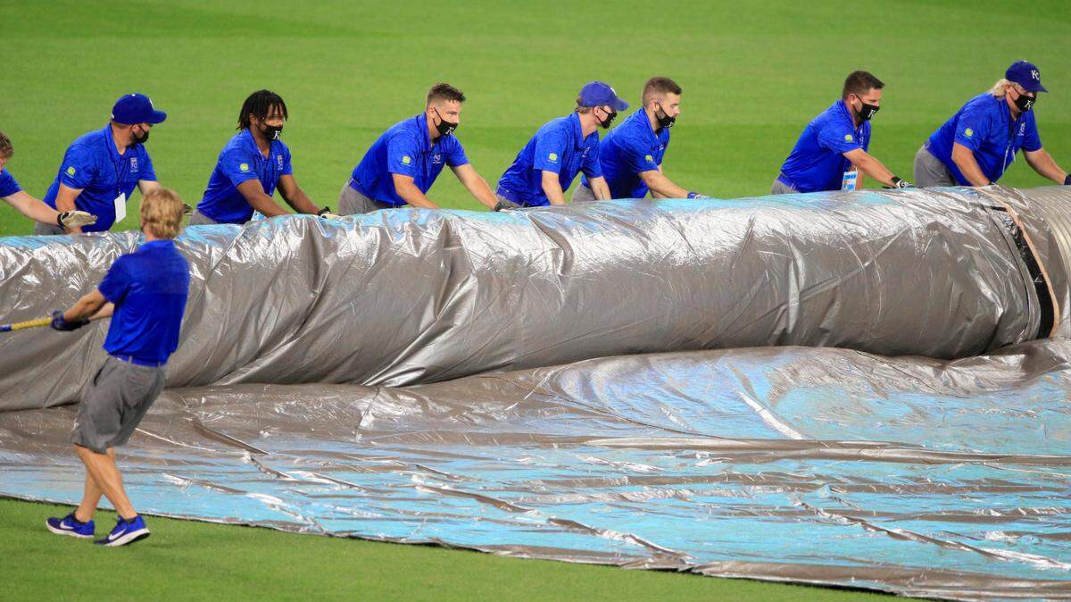 Grounds crew rolls up the tarp after a short rain delay during the fifth inning of a baseball game between the Kansas City Royals and the Minnesota Twins at Kauffman Stadium in Kansas City, Mo., Friday, Aug. 7, 2020. (AP Photo/Orlin Wagner)