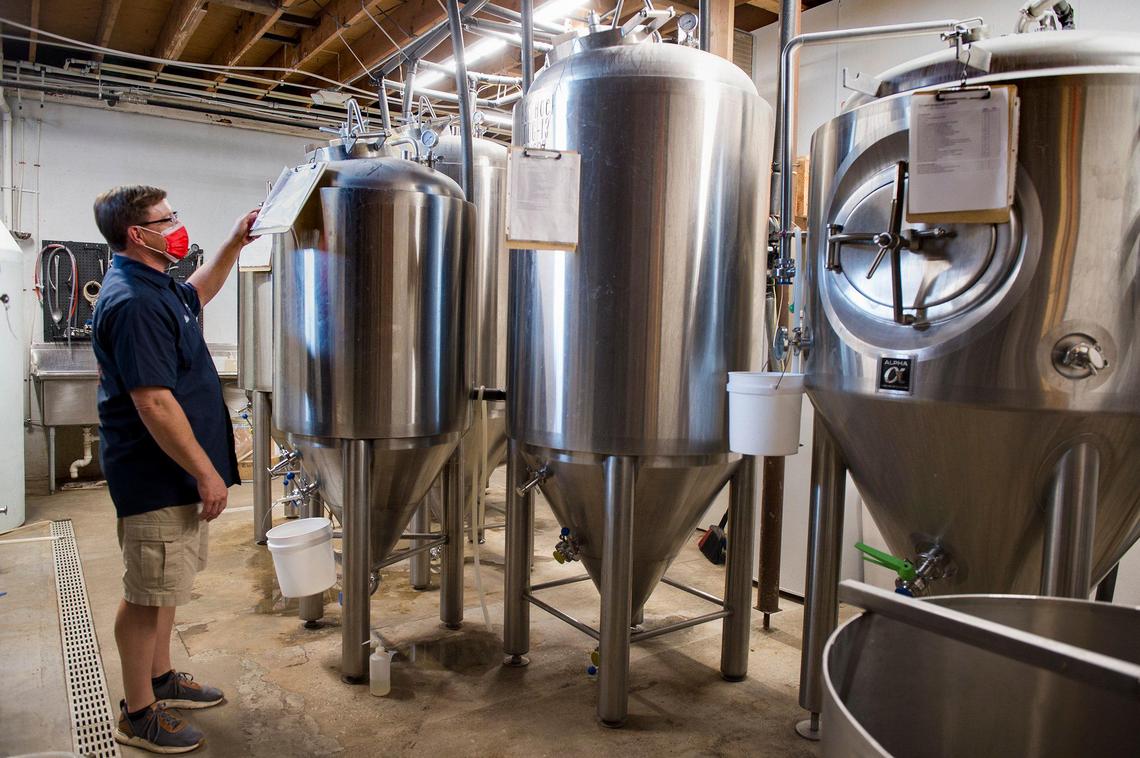 Mike McVey, owner of Transport Brewery, looks over stainless steel tanks at the craft brewery in Shawnee. He is hoping Johnson County voters will repeal a law in November that he says makes it difficult for small bars to survive. 