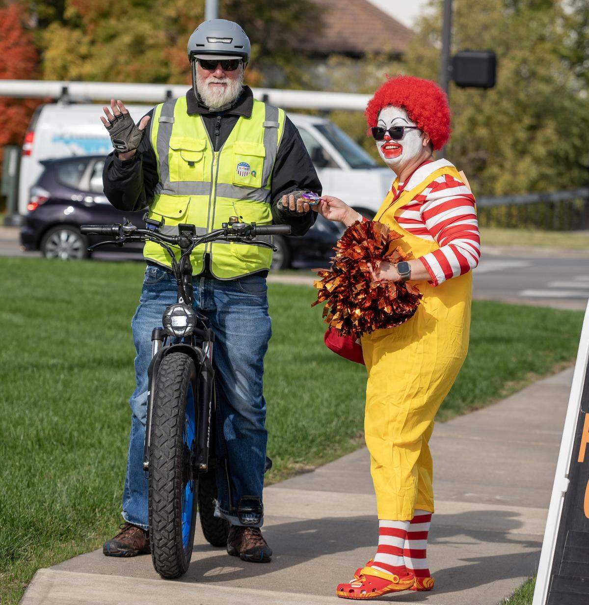 Dawn Wyatt, dressed as Ronald McDonald, hands out candy to a bicyclist during Russell Stover's annual Halloween candy giveaway at the company's headquarters on Friday, Oct. 31, 2025, in Kansas City.