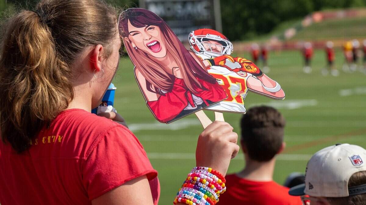 In August 2024, a young Chiefs fan wearing a wristful of friendship bracelets held up cardboard cutouts of Taylor Swift and Travis Kelce during practice at Chiefs training camp.