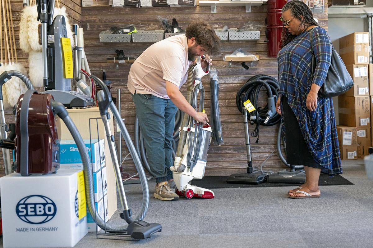 Logan Place, left, fixes a problem on a vacuum for customer Faith DaShawn, of Kansas City, at Erv’s Vacuums, 1800 E Santa Fe St., in Olathe. The store is one of many properties expected to be acquired by the city of Olathe.