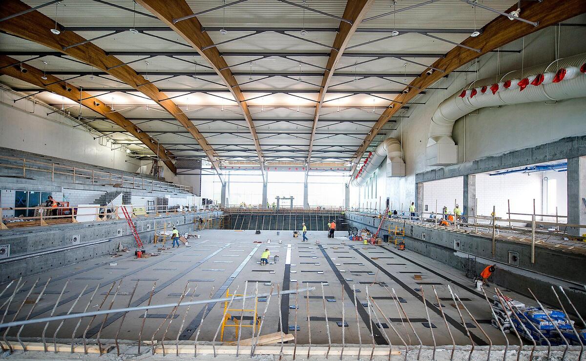 Works are laying tile and spreading sealant on the Olympic-size pool at the aquatic center. They hope to fill it with water soon.